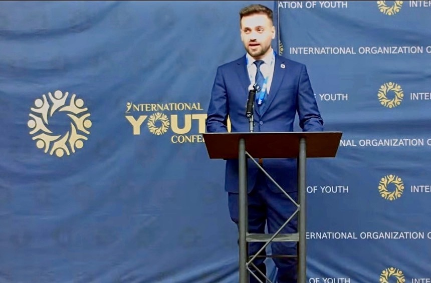 Umut Tutug speaking at a lectern at the International Youth Conference 14 in New York