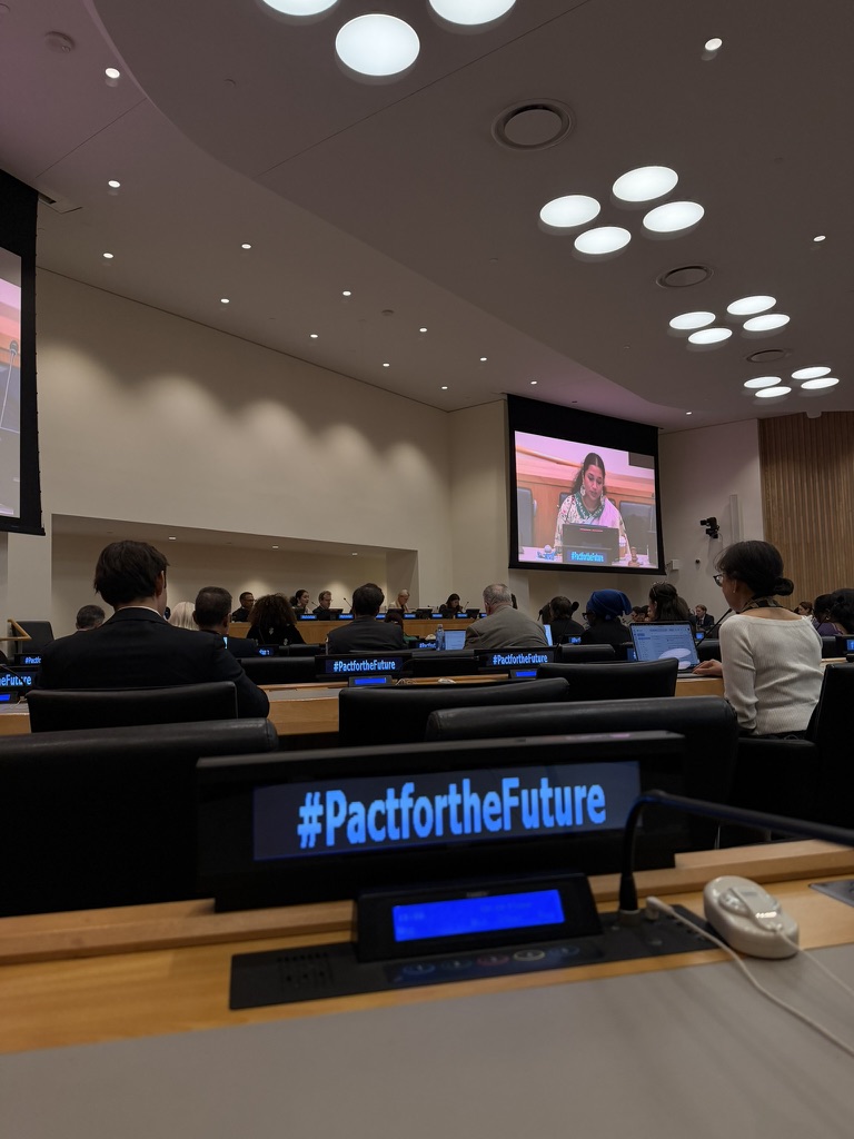 A UN conference room during UNGA81 week, with a #PactfortheFuture nameplate in the foreground