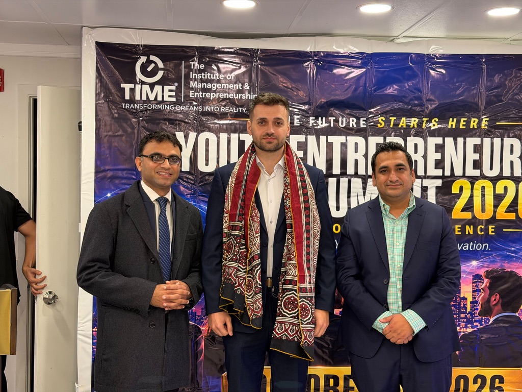 Umut Tutug with two organizers in front of the Youth Entrepreneurship and AI Summit 2026 banner
