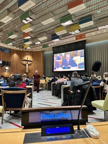 A youth-led peace session in a UN conference room, seen from a delegate seat